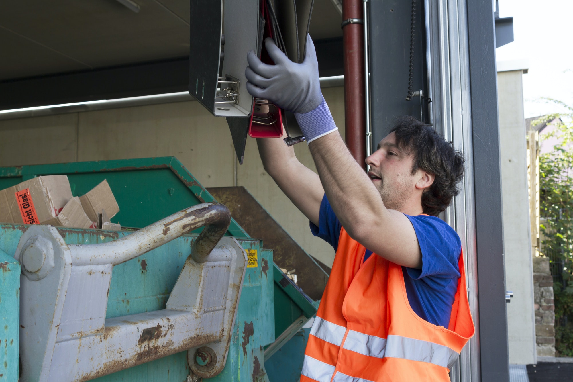 worker-at-a-waste-container-throwing-away-folders.jpg worker-at-a-waste-container-throwing-away-folders.jpg